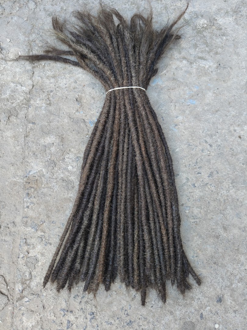 A bundle of dark brown dreadlocks tied with a white band on a concrete surface.