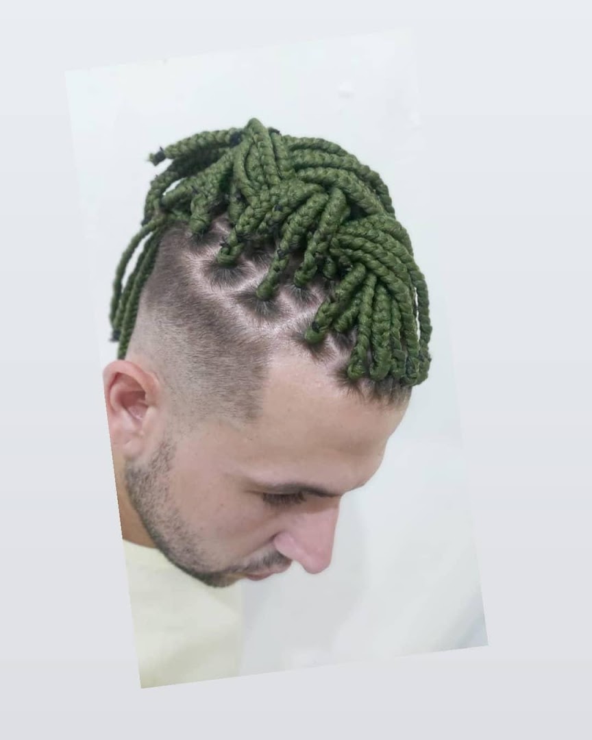 A man with stylish green box braids and a faded haircut.