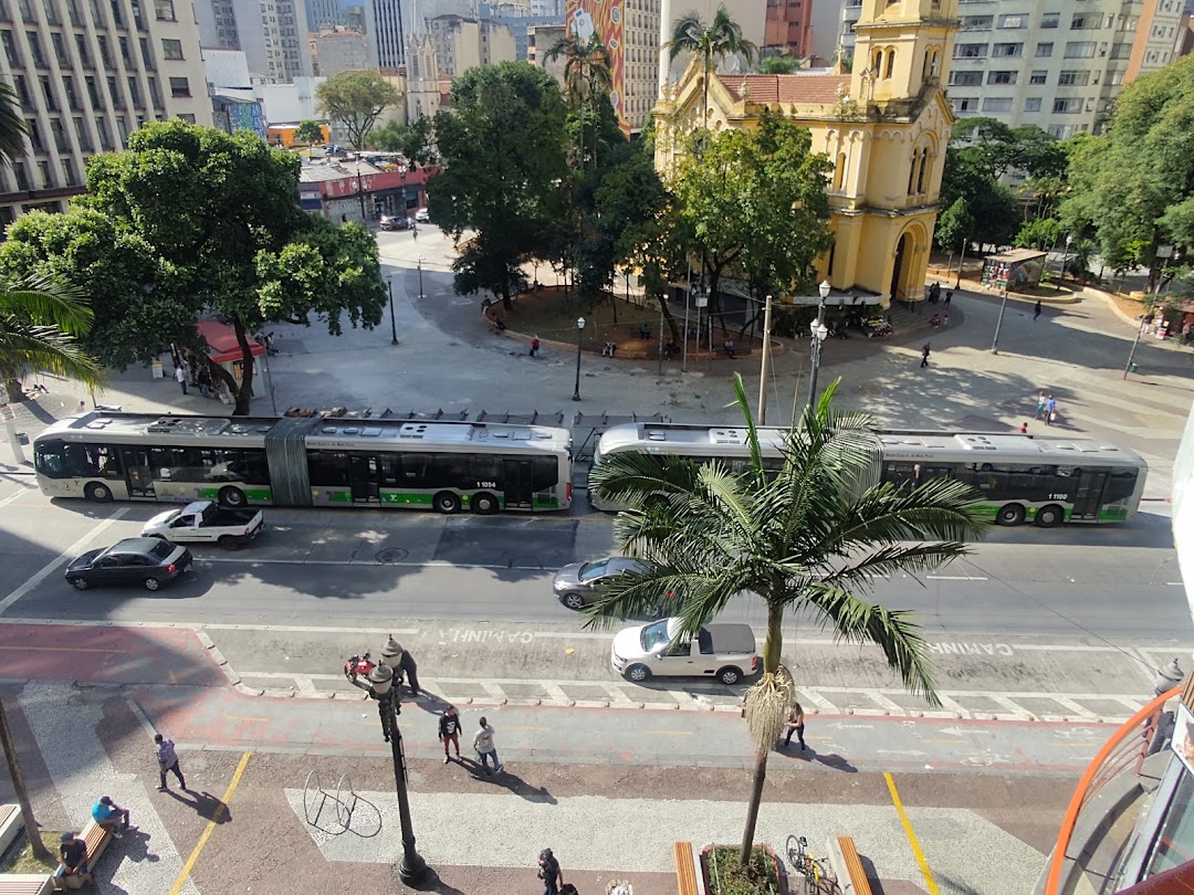An aerial view of a city street with buses, cars, people, and a yellow church.