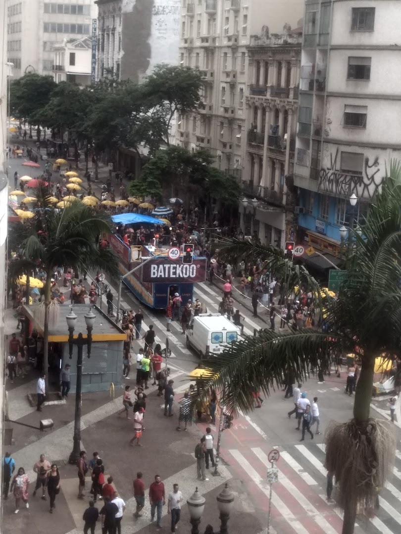 A busy street scene with a parade float, crowds of people, and palm trees.