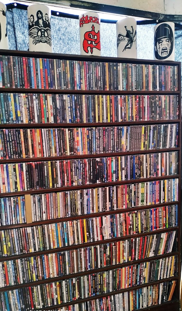 A wall of shelves filled with DVDs and CDs, topped with decorative cylinders.