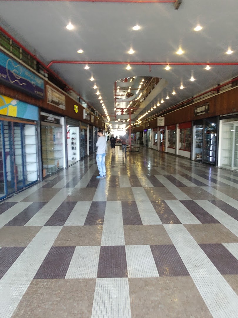 A person stands in a long, well-lit shopping arcade with shops on either side.