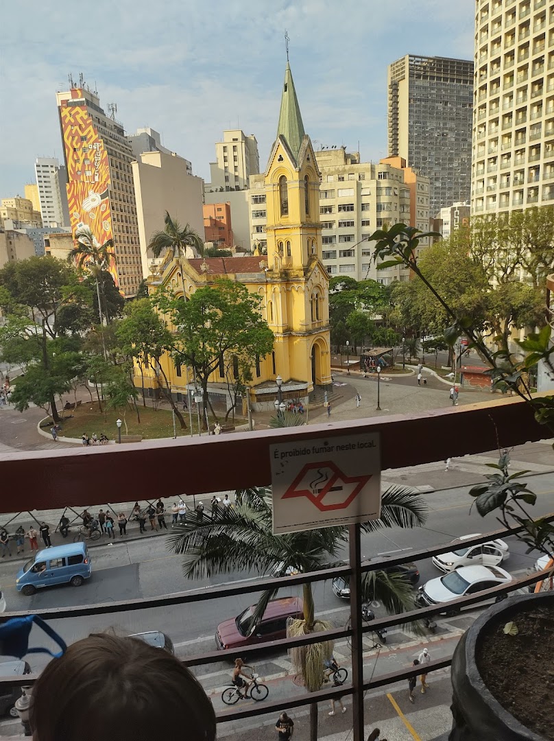 View of a yellow church and city skyline from a balcony with a no smoking sign.