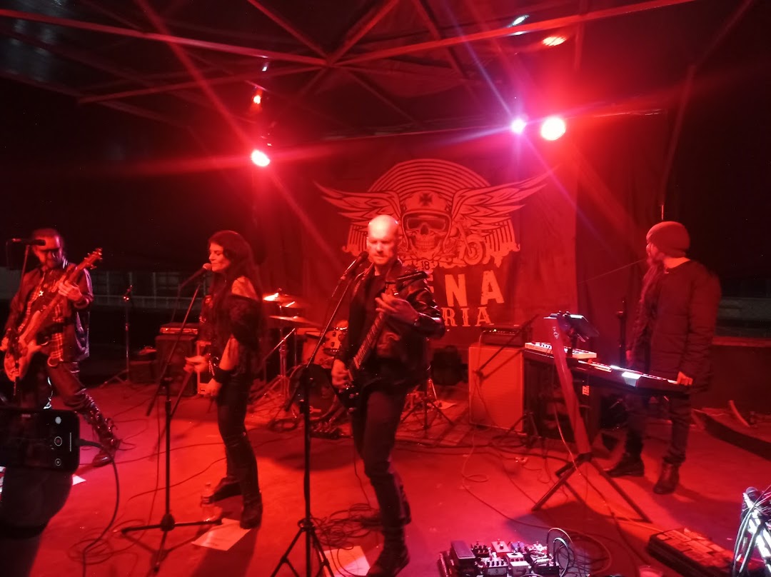 A band performs on stage under red lighting with a banner displaying the shop name.