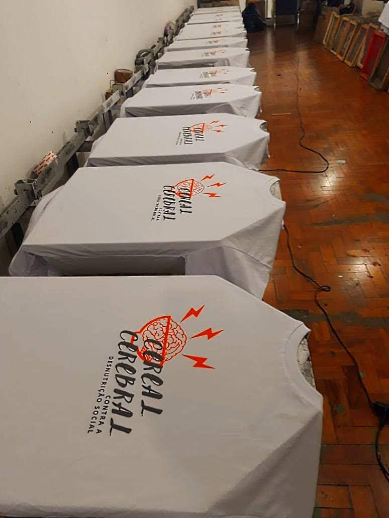 A row of white t-shirts with a red and black graphic design are laid out on a table.