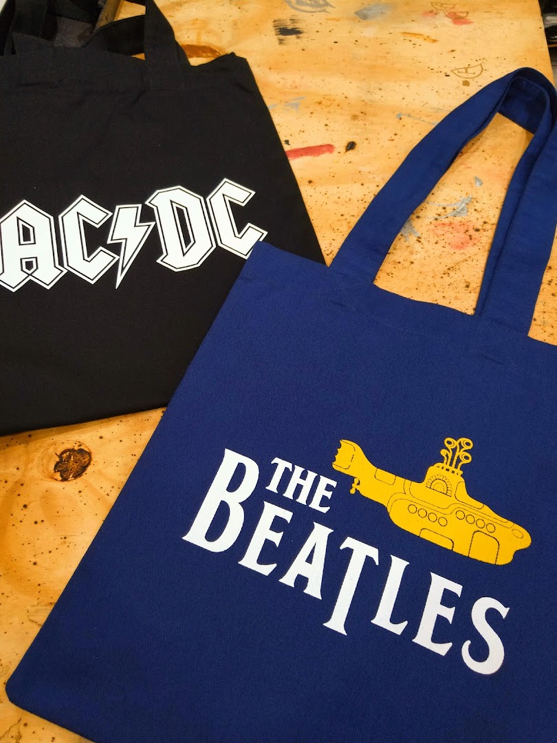 Two tote bags, one black with AC/DC logo, one blue with The Beatles logo.