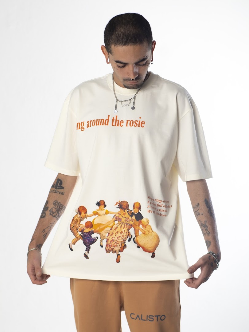A man models a cream t-shirt with a vintage children's ring-around-the-rosie graphic and text.