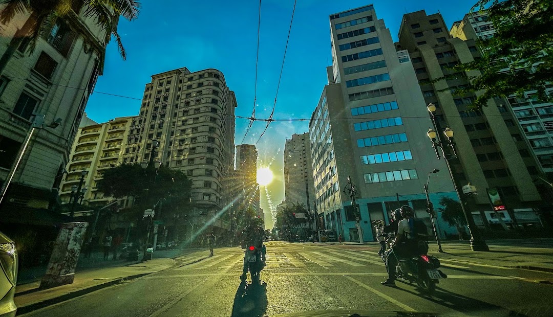 A street view of Avenida São João with buildings and traffic under a bright sun.