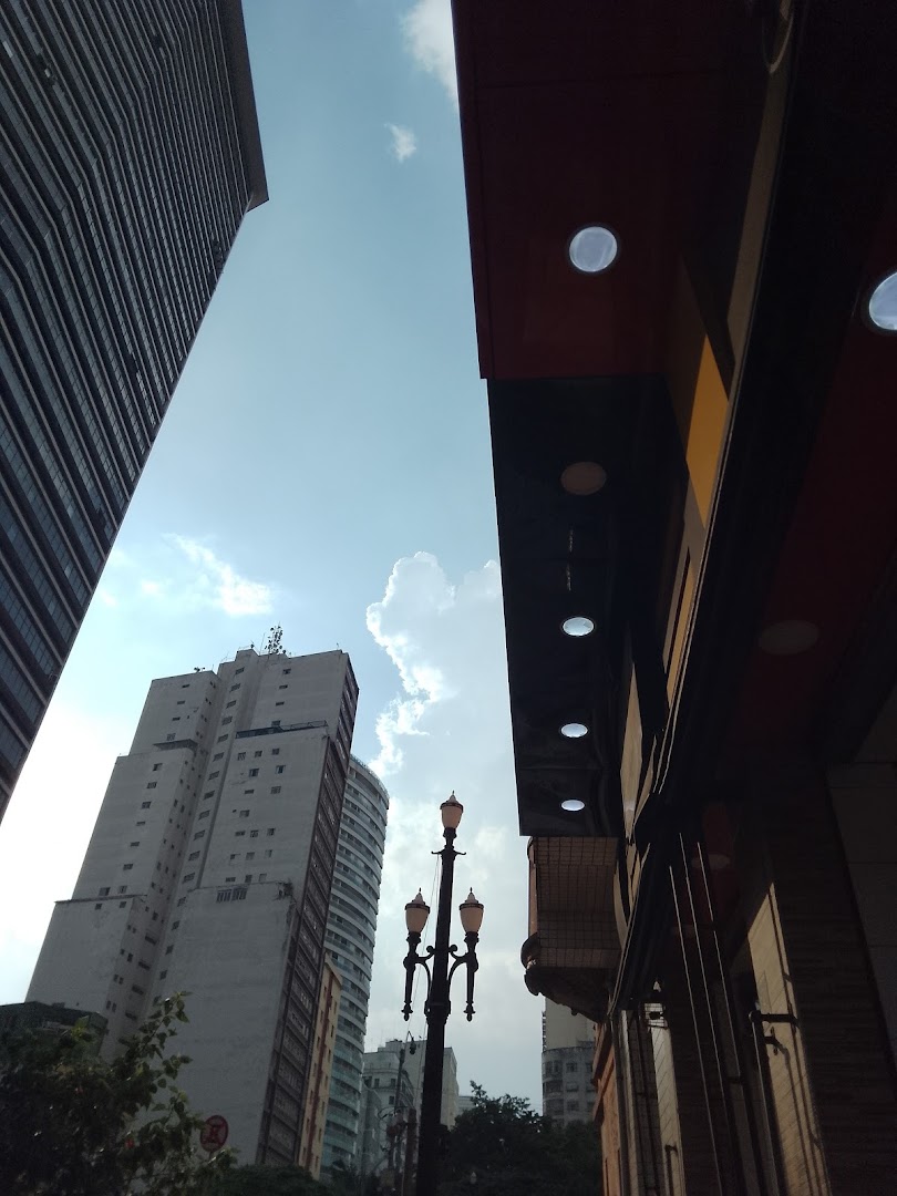 View of tall buildings and a street lamp against a cloudy sky.