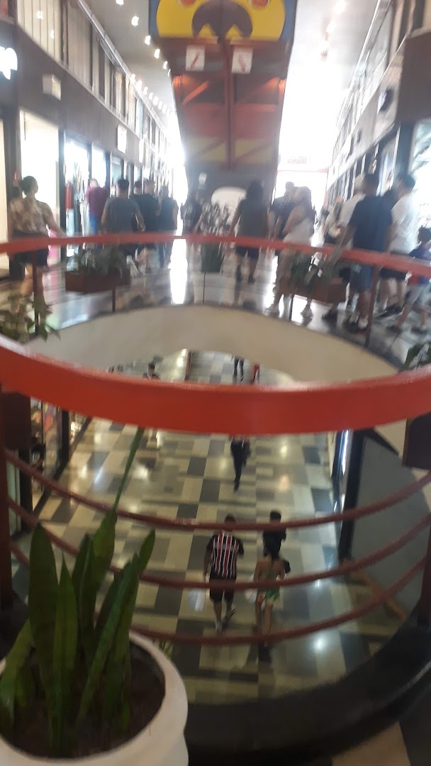 People walking in a shopping mall with a large colorful structure overhead.