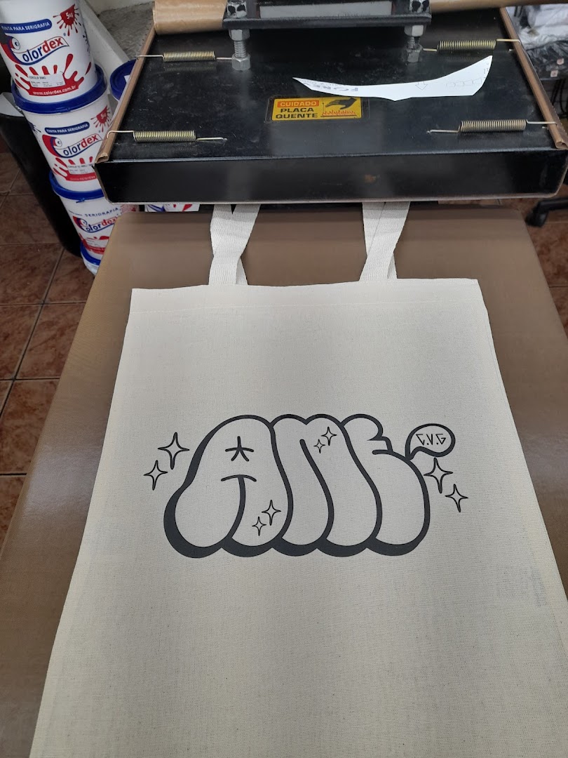 A tote bag with a graffiti-style design being printed using a heat press machine.