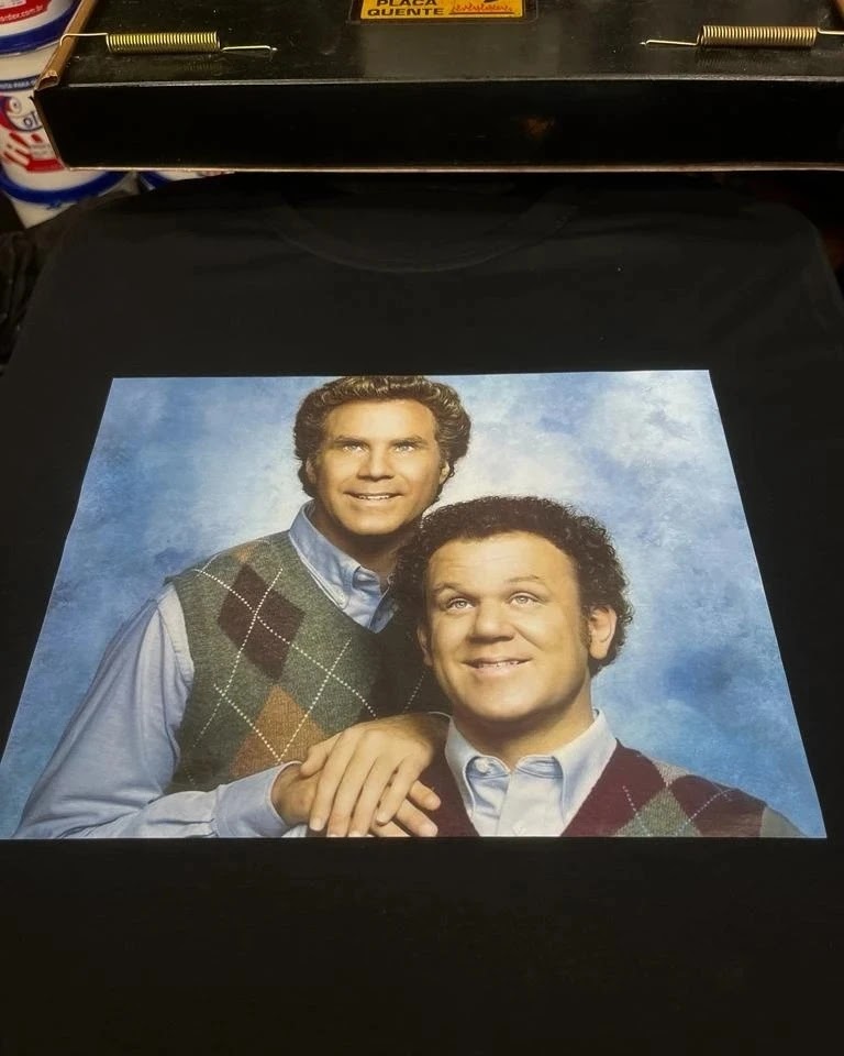 A black t-shirt with a printed image of two smiling men wearing argyle sweaters.