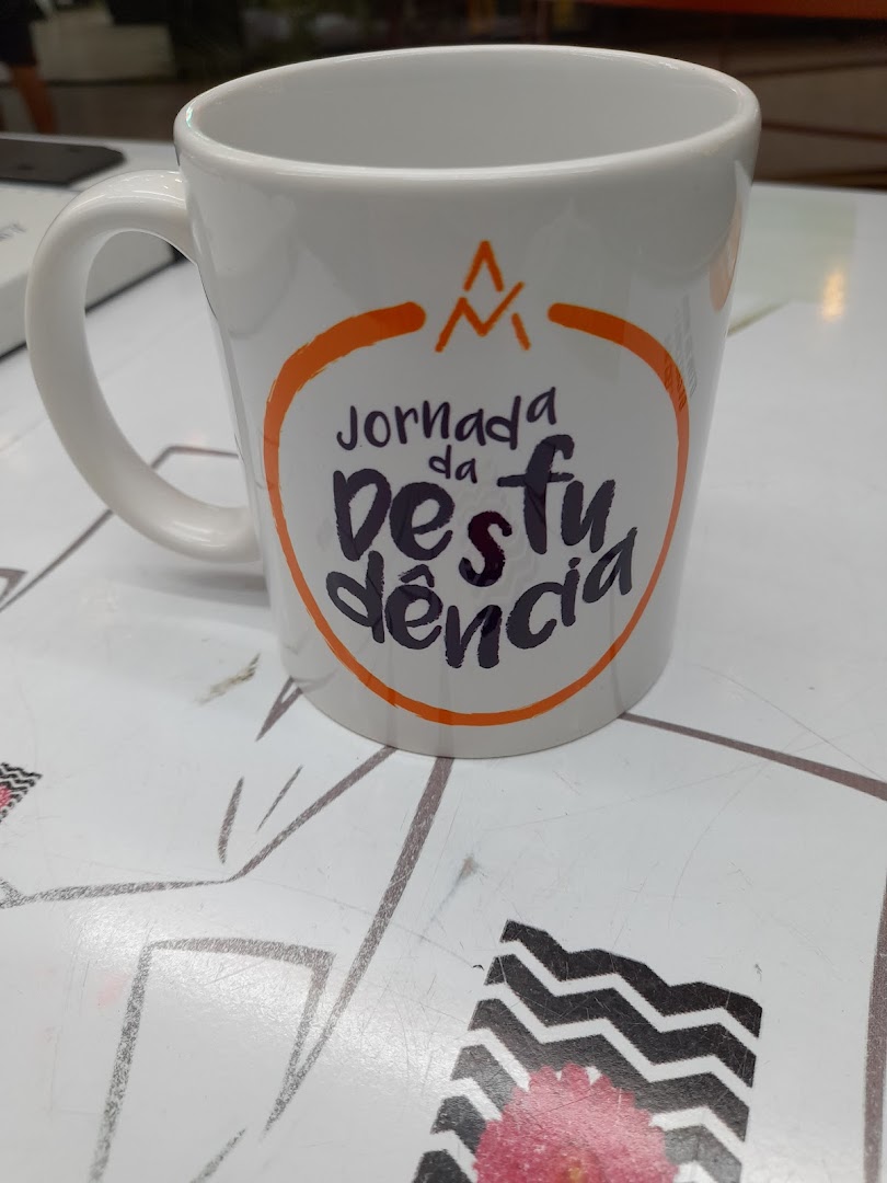 A white mug with orange and purple text and a logo sits on a patterned surface.