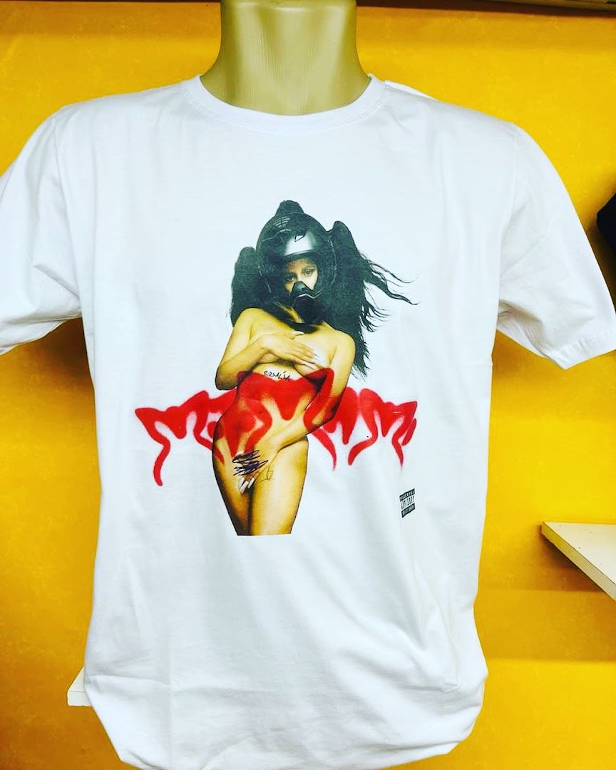 A white t-shirt with a striking graphic print of a woman wearing a helmet and mask.