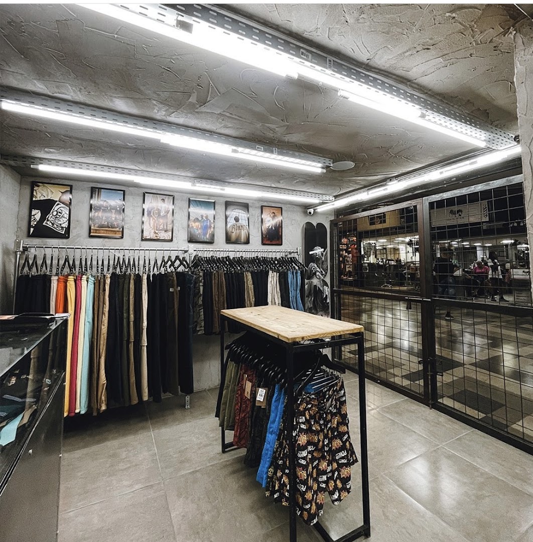 Interior of a clothing store with racks of pants and patterned shorts.