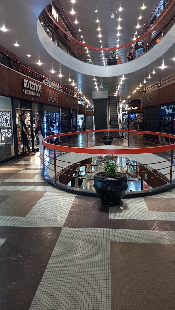 Interior view of a multi-level shopping mall with shops and escalators.