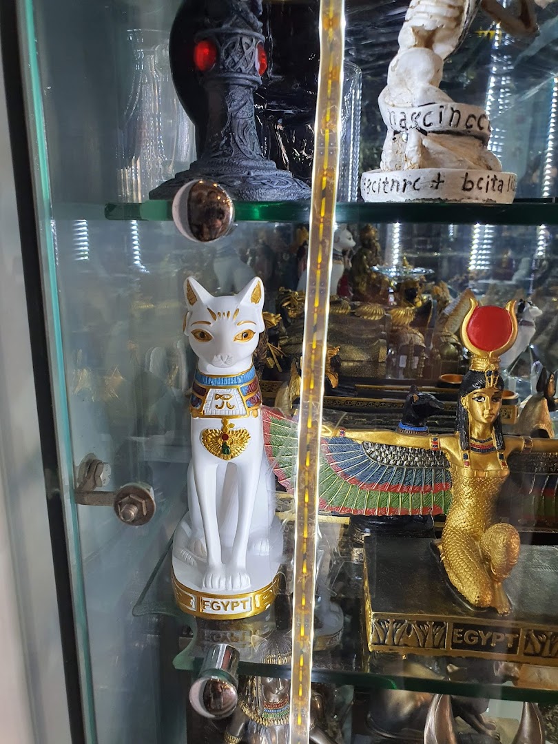 A display cabinet filled with Egyptian-themed statues and artifacts, including a white cat statue.