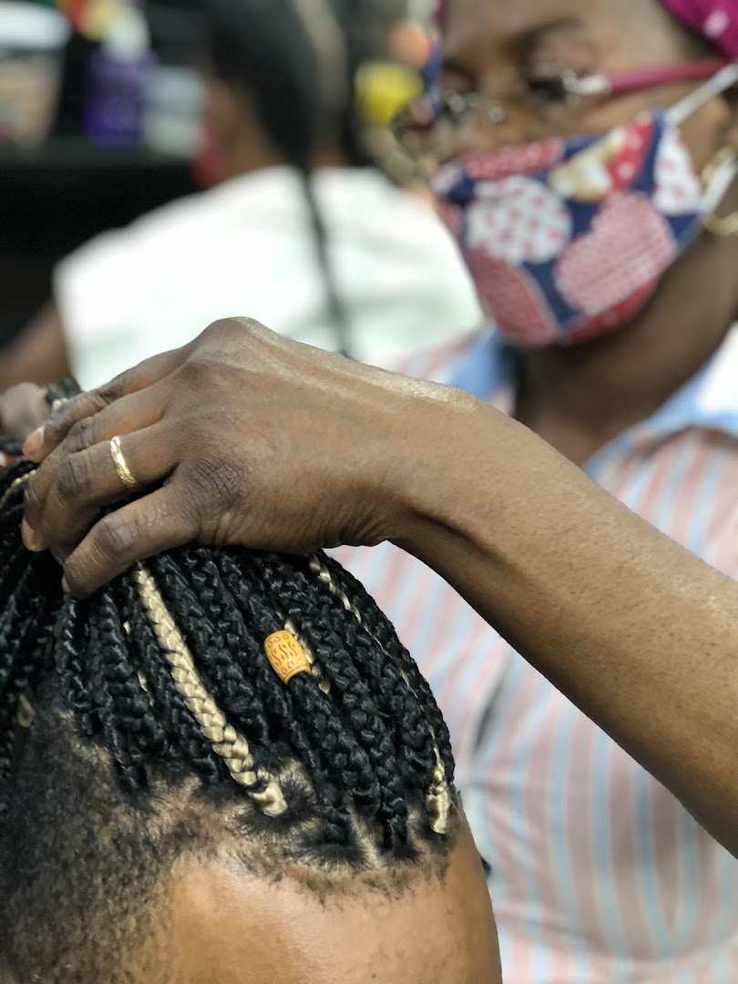 A hairstylist braids hair, adding beads to the braids.