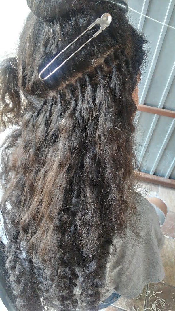 A close-up of a person's hair being styled with extensions and a clip.