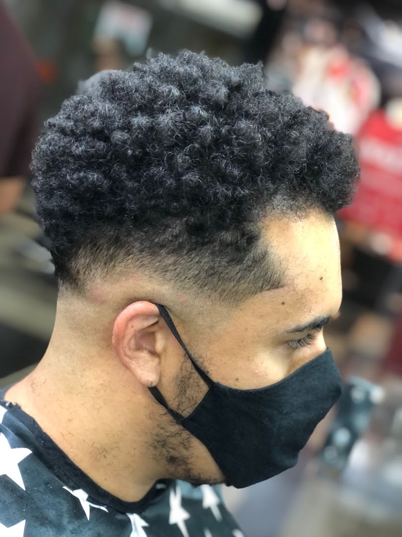A close-up profile of a man with a stylish haircut and a black face mask.