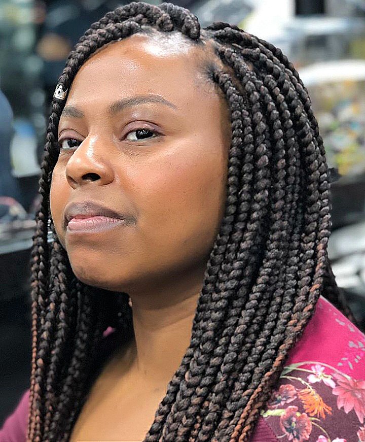 A woman with stylish box braids and a floral top.