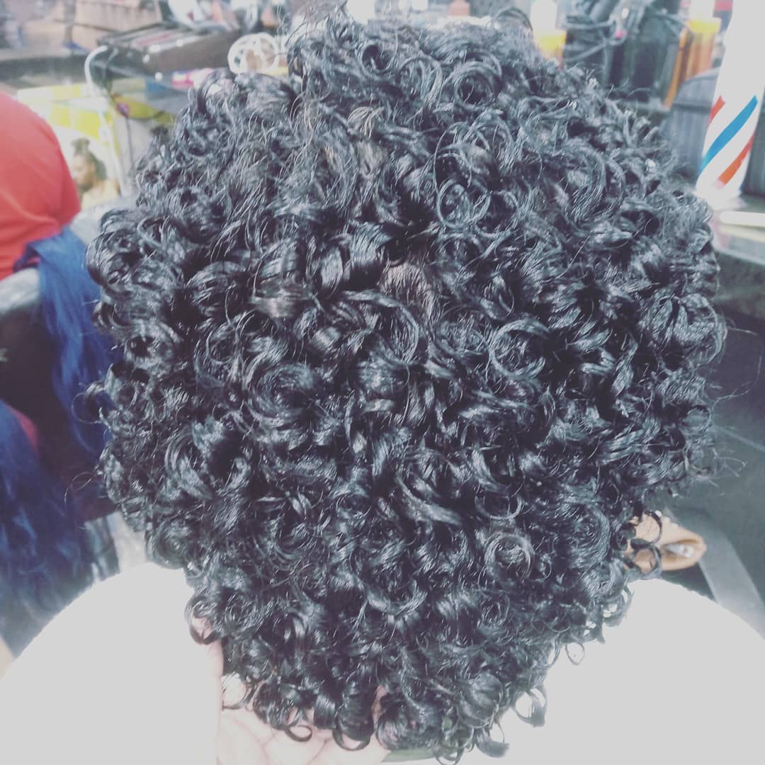 A close-up view of a person's head with perfectly styled curly hair.