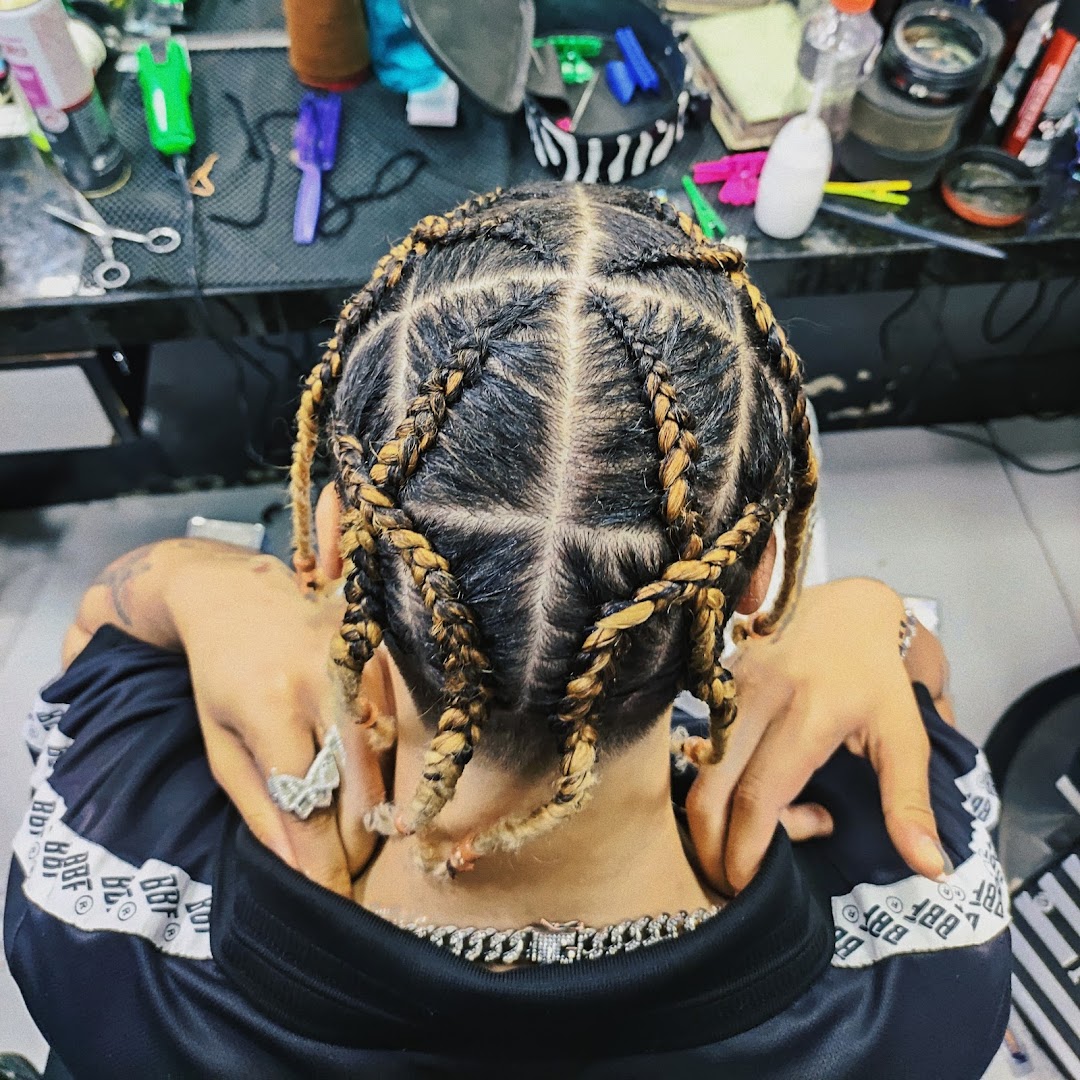A person's head from above, showcasing intricate braided hairstyles with blonde highlights.