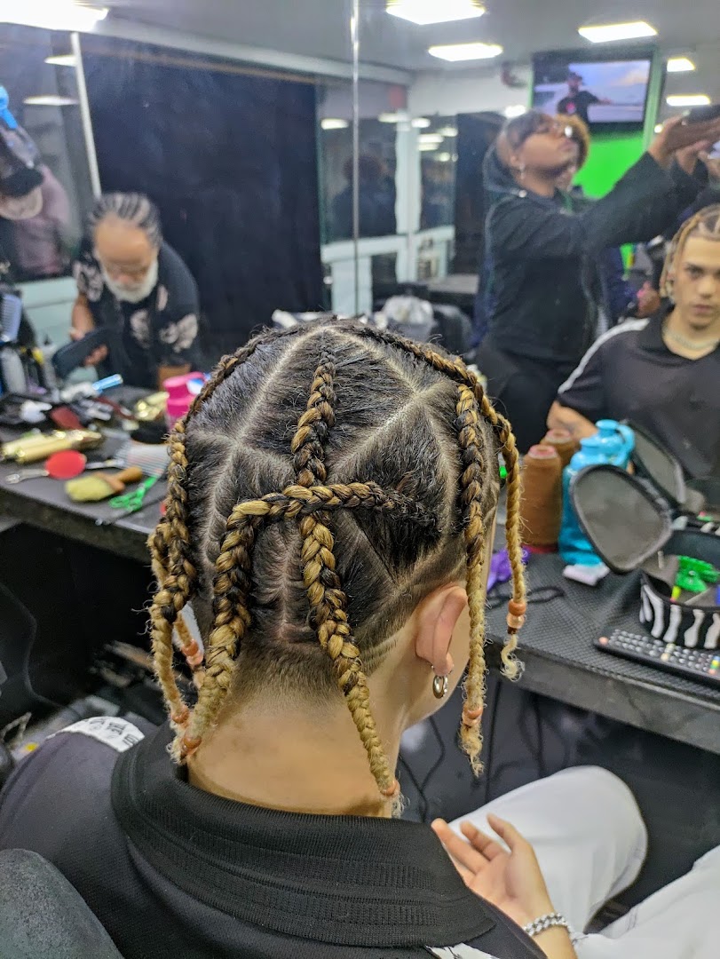 A person with intricate braided hair is getting their hair styled at a salon.