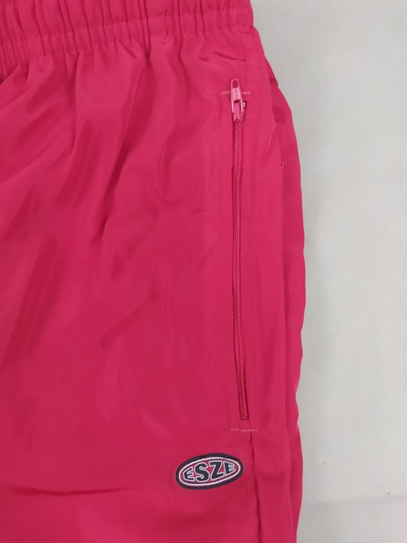 Close-up of bright pink athletic shorts with a zippered pocket and the Esze logo.