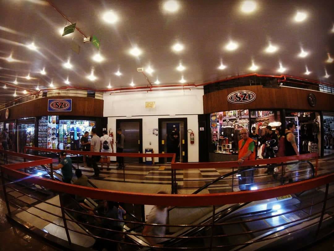 A view of the Esze shop entrance with displays of clothing and accessories, and shoppers nearby.