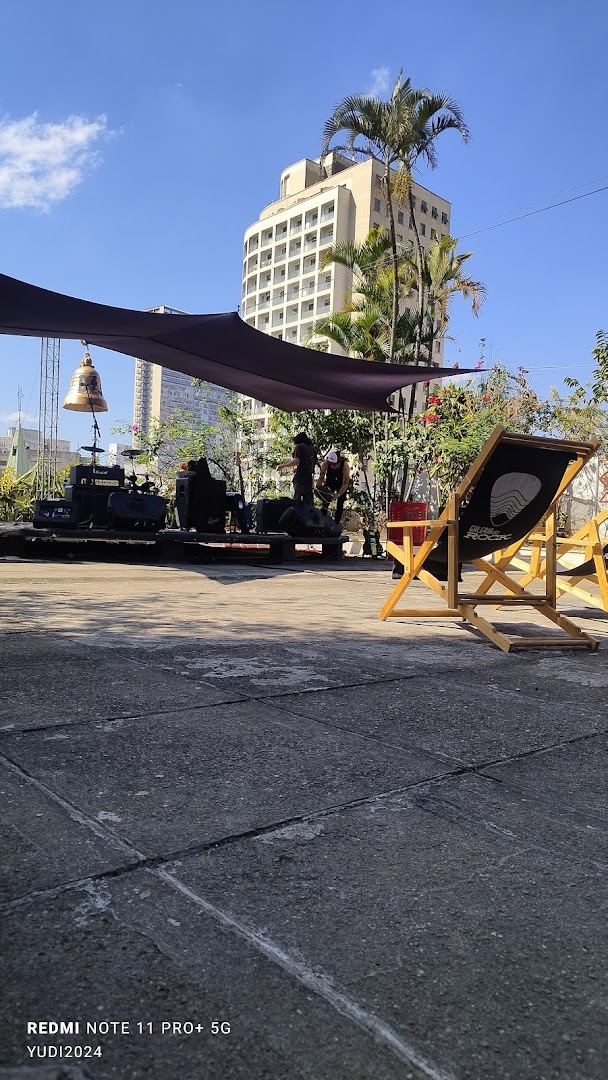 Outdoor seating area with a stage setup and a deck chair, under a canopy.