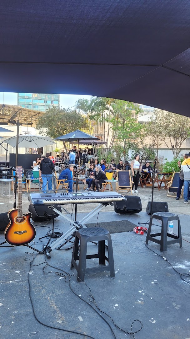 An outdoor seating area with a stage setup featuring musical instruments and people enjoying themselves.