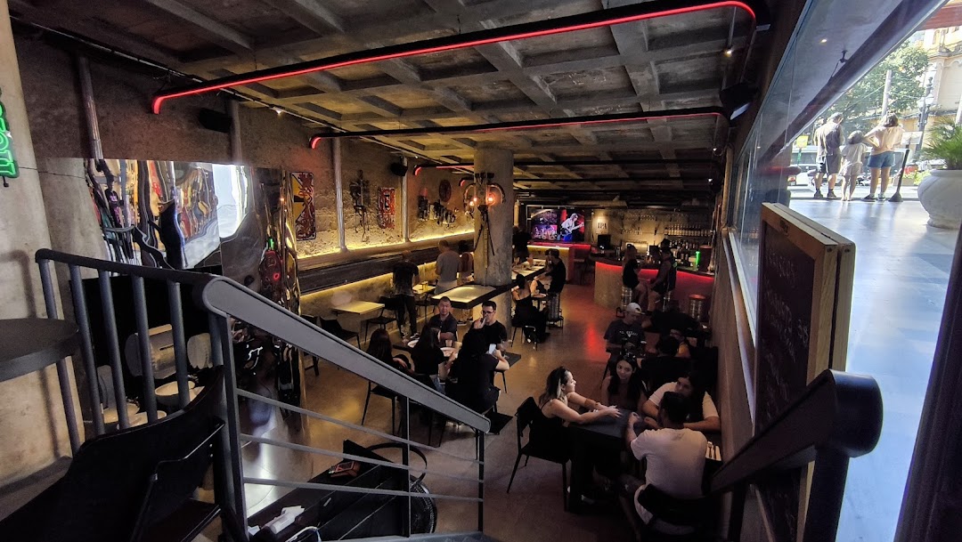 Interior view of a bar with people seated at tables and a bar area.