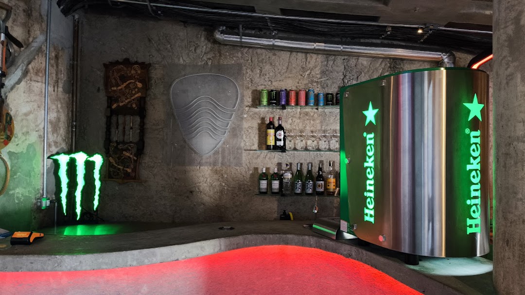 A bar counter with Heineken branding, bottles, glasses, and Monster Energy signage.
