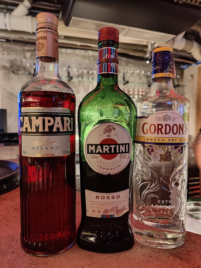 Three bottles of alcoholic beverages: Campari, Martini Rosso Vermouth, and Gordon's London Dry Gin.