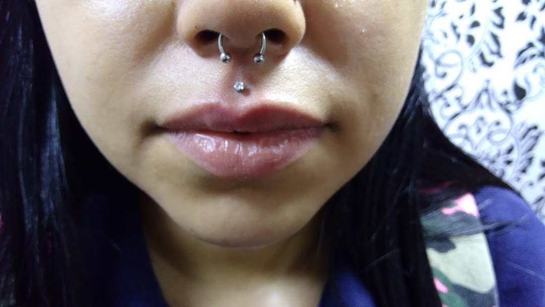 Close-up of a person's face with nose and lip piercings.