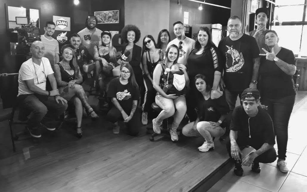 A group of people, likely artists and clients, posing for a photo inside a tattoo studio.