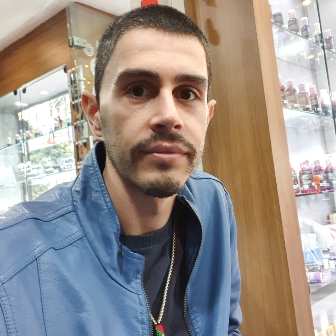 A man with a beard and mustache wearing a blue jacket inside a shop.
