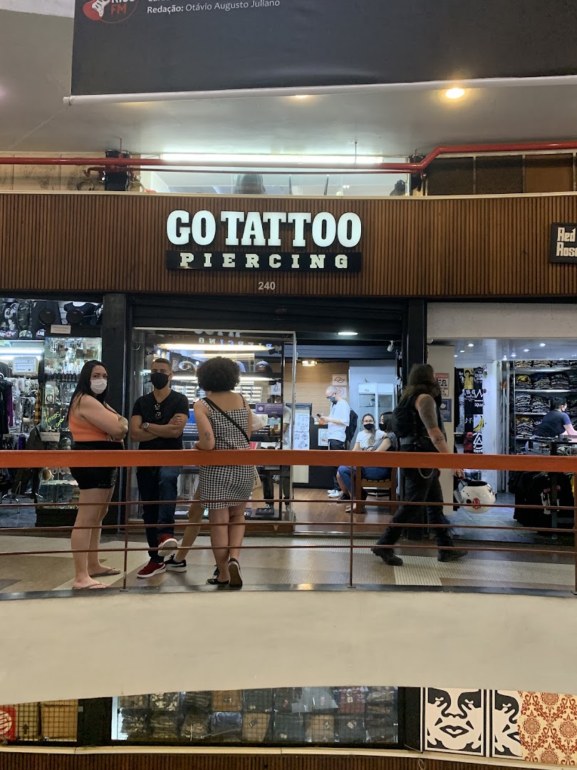 People stand outside a tattoo and piercing shop with a prominent sign.