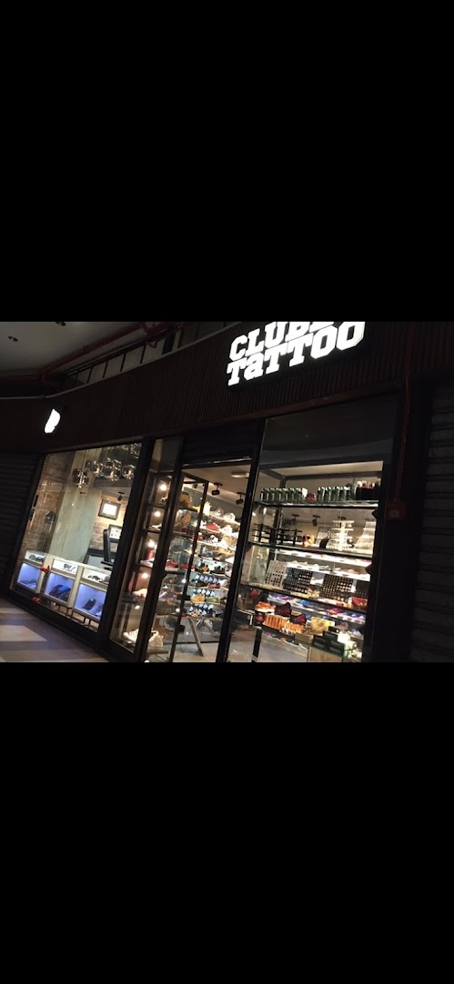 The exterior of a tattoo and piercing shop with a prominent sign and display windows.