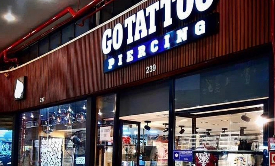 The exterior of a tattoo and piercing shop with a prominent illuminated sign.