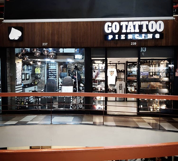 The exterior of Go Tattoo Piercing shop, showcasing tattoo chairs and merchandise.
