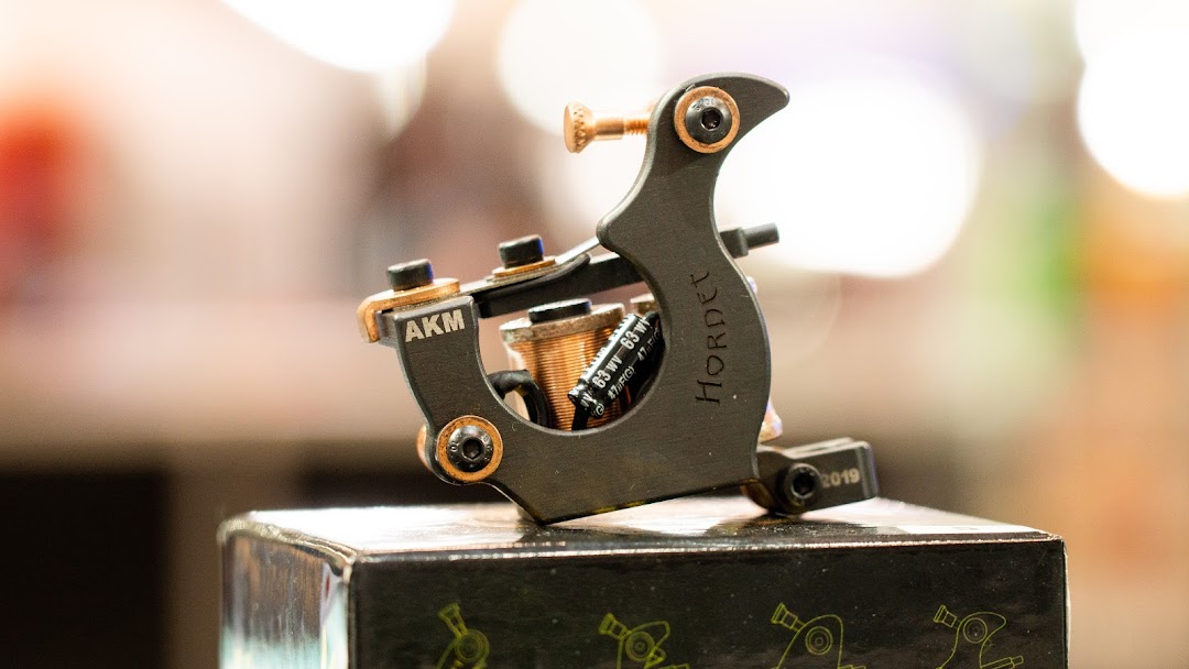 A close-up of a black tattoo machine with 'HORDET' and 'AKM' branding.