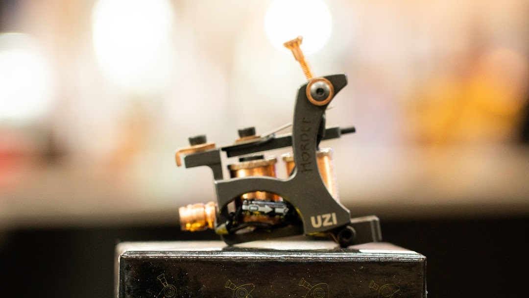 A close-up of a tattoo machine with 'HORNET' and 'UZI' visible.