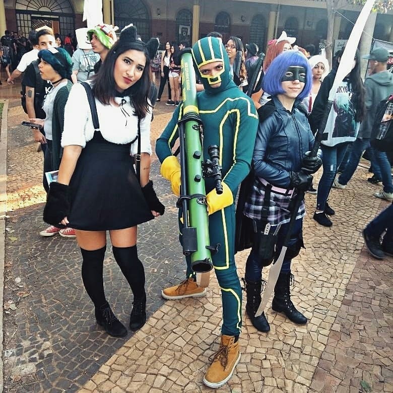 Three people in cosplay costumes, one holding a prop rocket launcher, at an outdoor event.