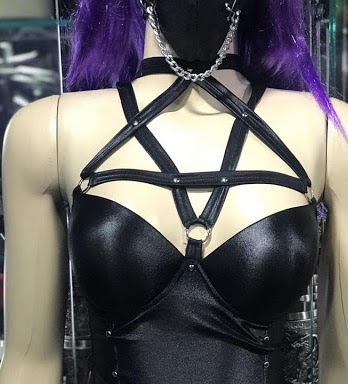 Mannequin wearing a black pentagram harness and mask with chains.