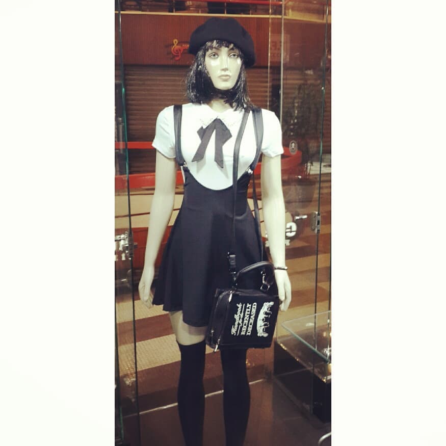 Mannequin in a black dress, white shirt, beret, and thigh-high socks.