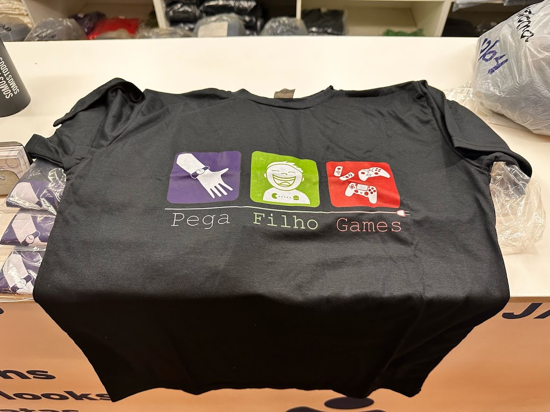 A black t-shirt with a gaming-themed graphic and text 'Pega Filho Games'.
