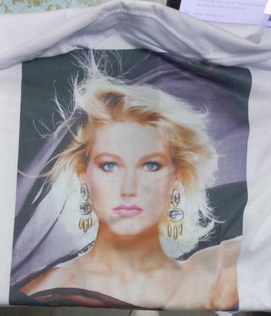 A white t-shirt featuring a vintage-style print of a blonde woman with blue eyes and large earrings.