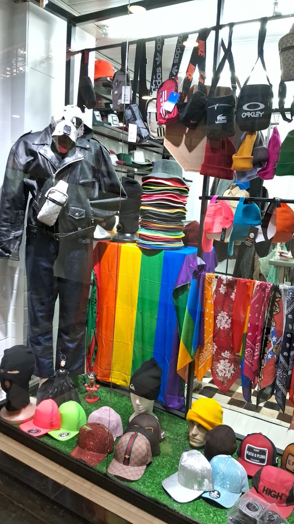 A shop window display featuring a mannequin in a leather jacket, hats, bags, and colorful scarves.